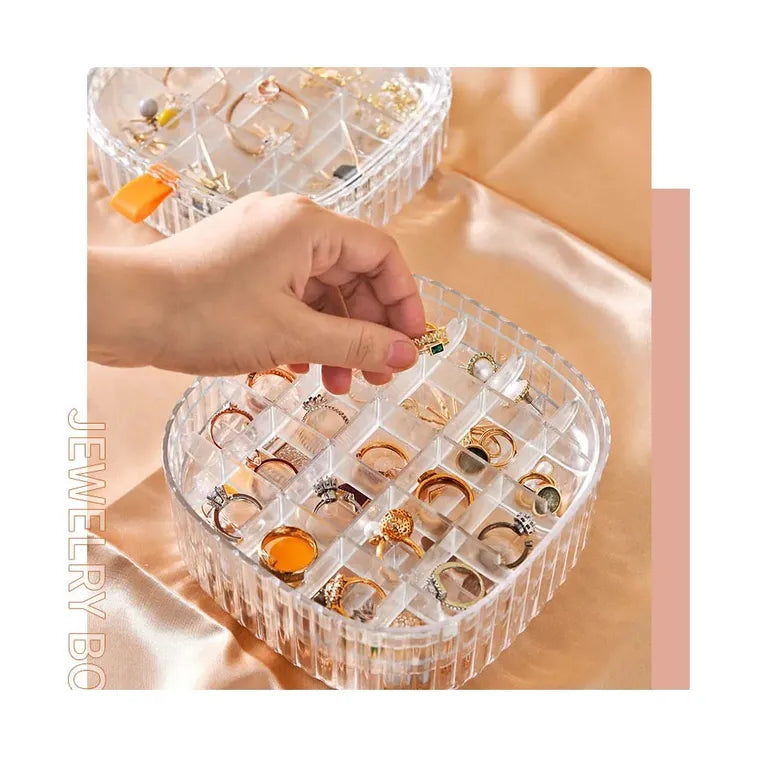 A cosmetic and jewelry storage box with a lid, containing rings and earrings neatly organized inside.
