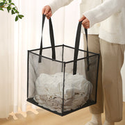 A person holding a foldable laundry basket full of clothes