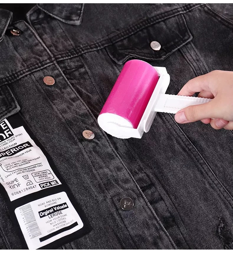 a hand rolling a pink Reusable Lint Remover on a denim jacket