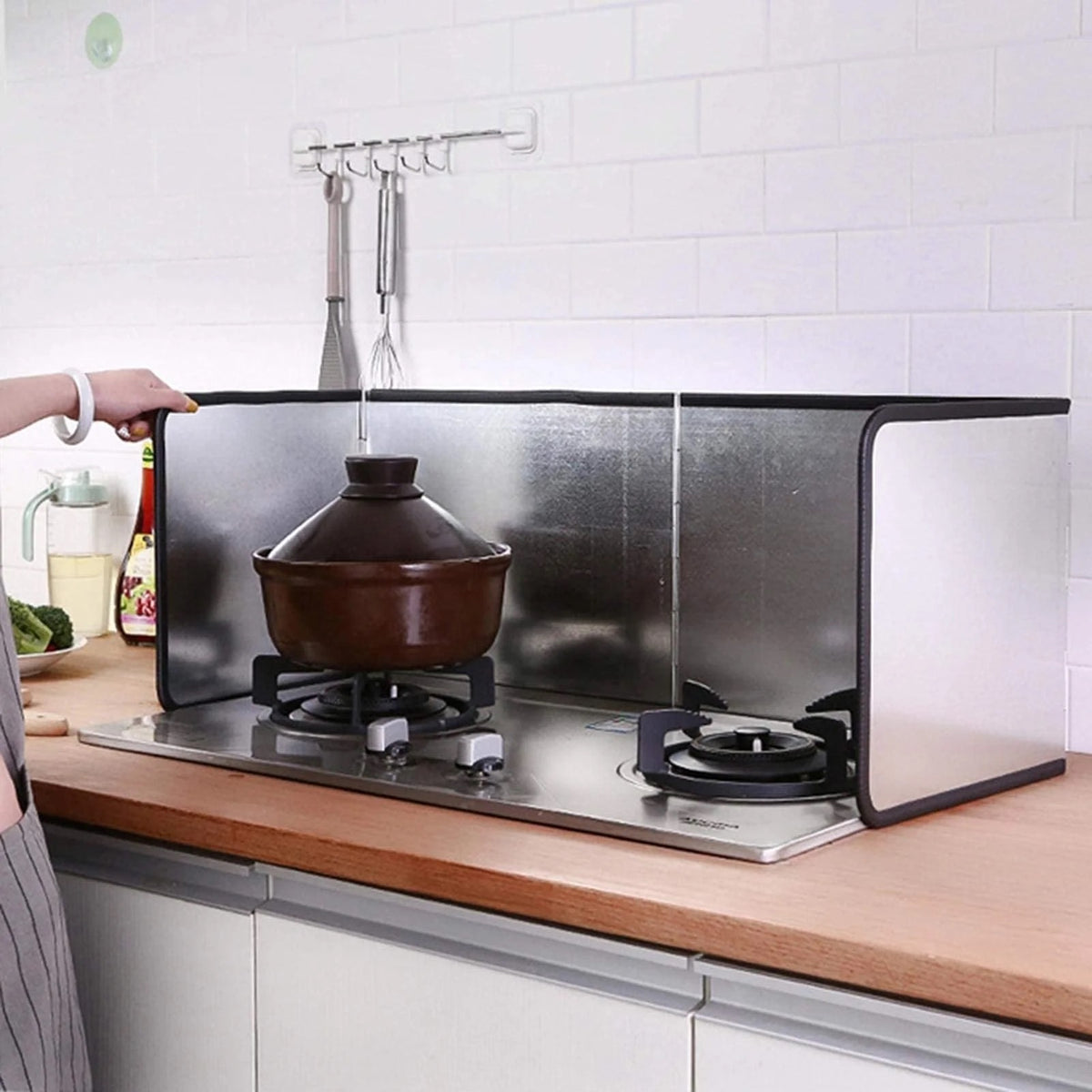 A woman placing a pot on a gas stove,utilizing an oil-blocking board