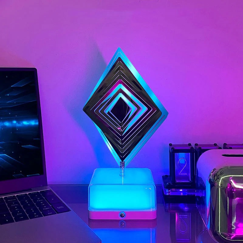 Diamond shape 3D Rotating Night Light placed next to a laptop on a table
