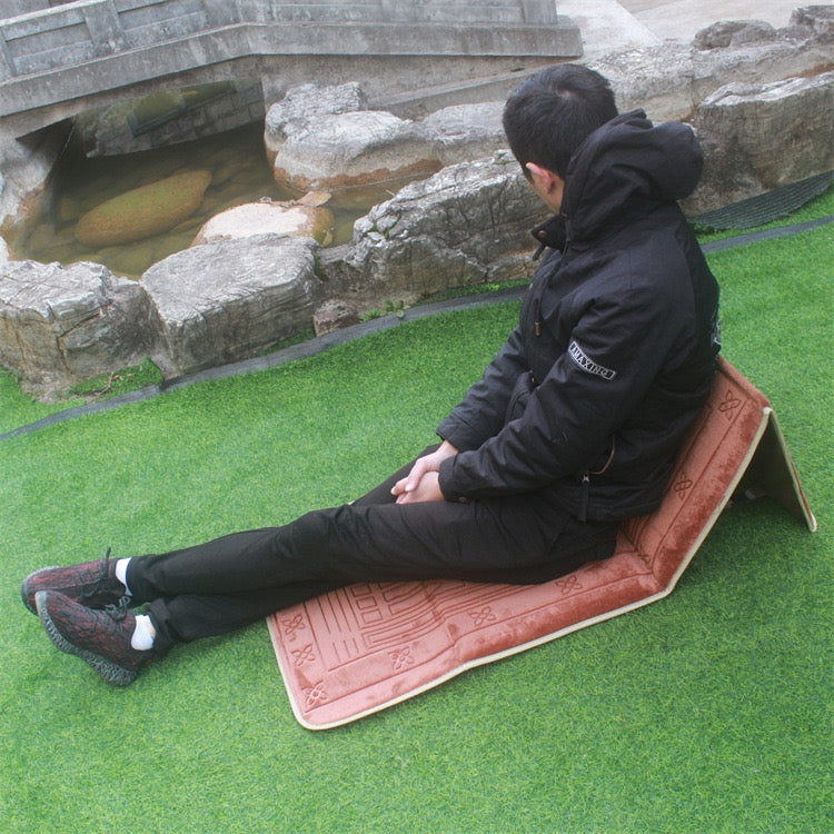 A person relaxing on Islamic Foldable Prayer Mat with backrest opened