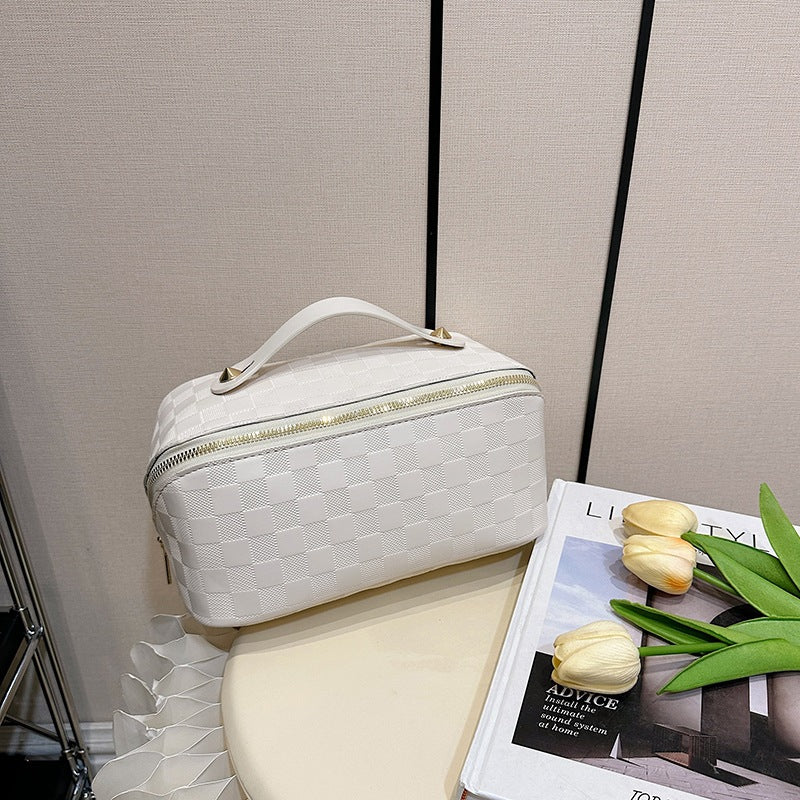 White color Cosmetic Bag kept next to a magazine and flowers on a table