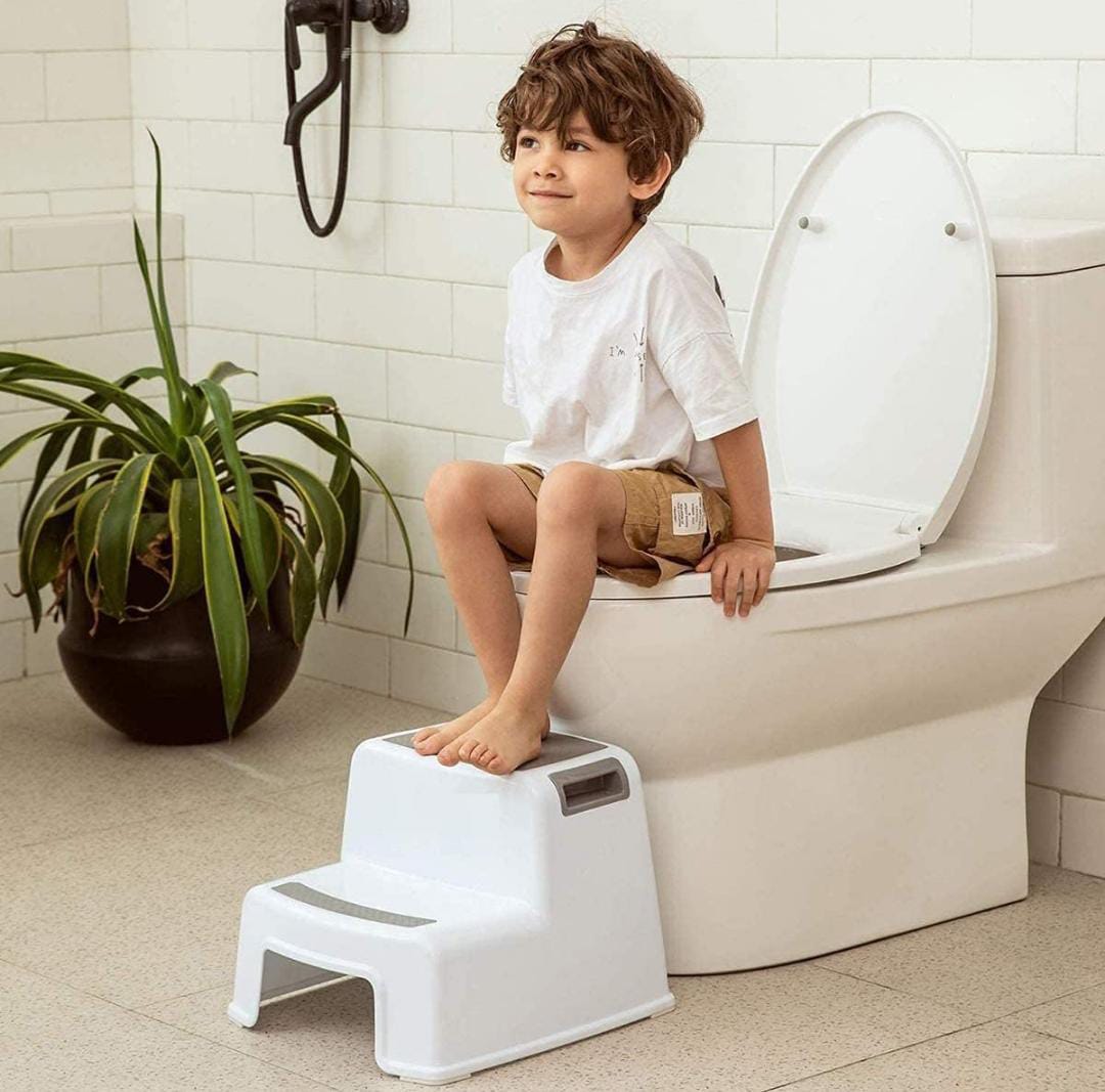 A Child is Using Kids Step Stool While Sitting On the Toilet.