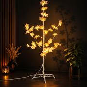 LED Blossom Tree Light Decoration with glowing lights on a stand in a dimly lit room.