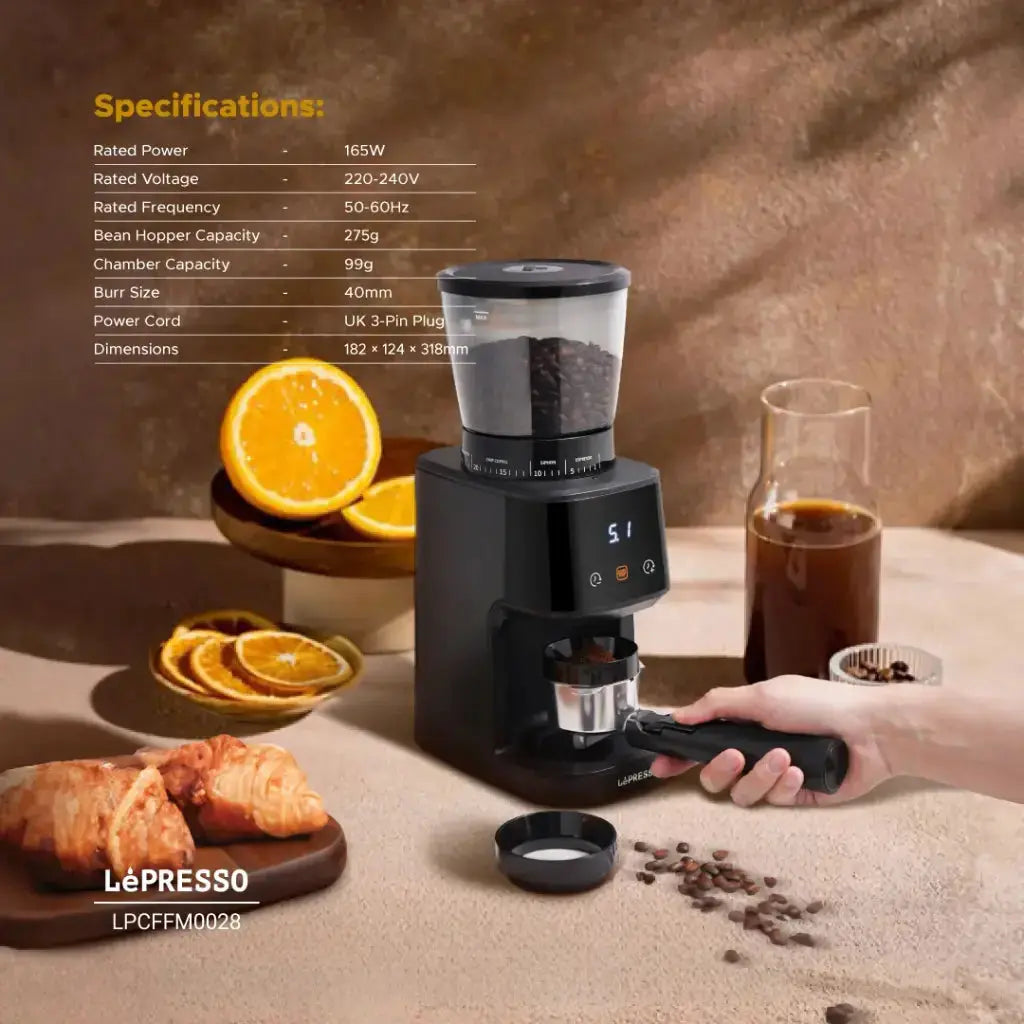 A premium lifestyle shot of a black Lepresso AeroGrind Conical Burr Coffee Grinder with croissants, coffee grounds, orange, iced coffee, and a portafilter, featuring a “Specifications” table in the top