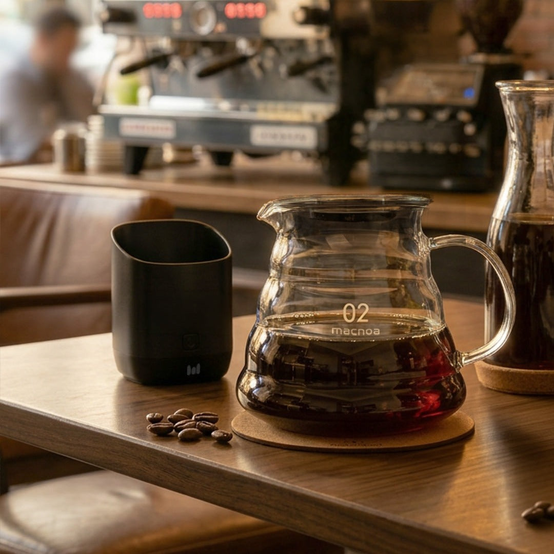 Macnoa MacDrip Server 02 with coffee on a wooden table in a coffee shop setting.