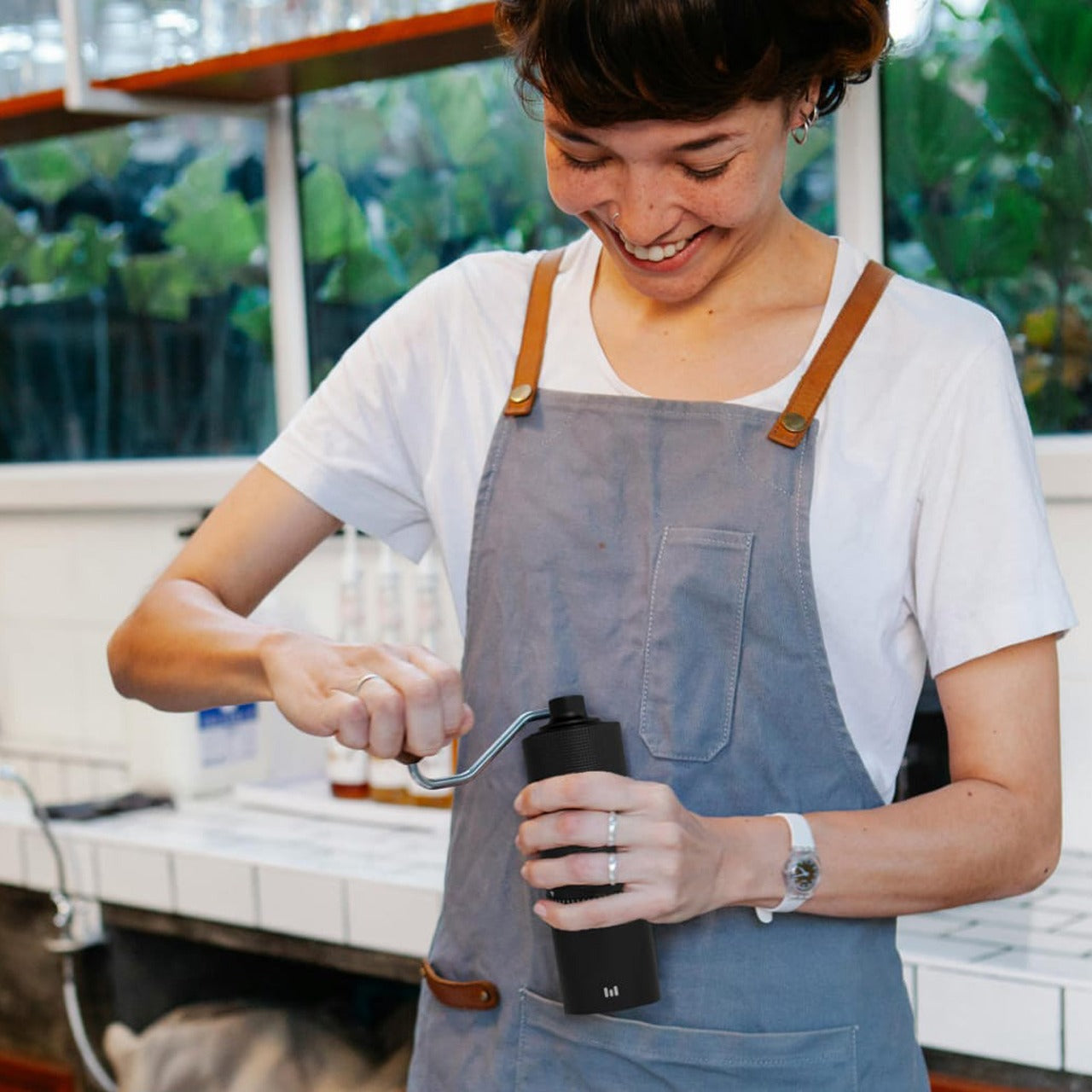 A Women is Making Coffee Using Macnoa MacGrind Craft - Manual Hand Coffee Bean Grinder.