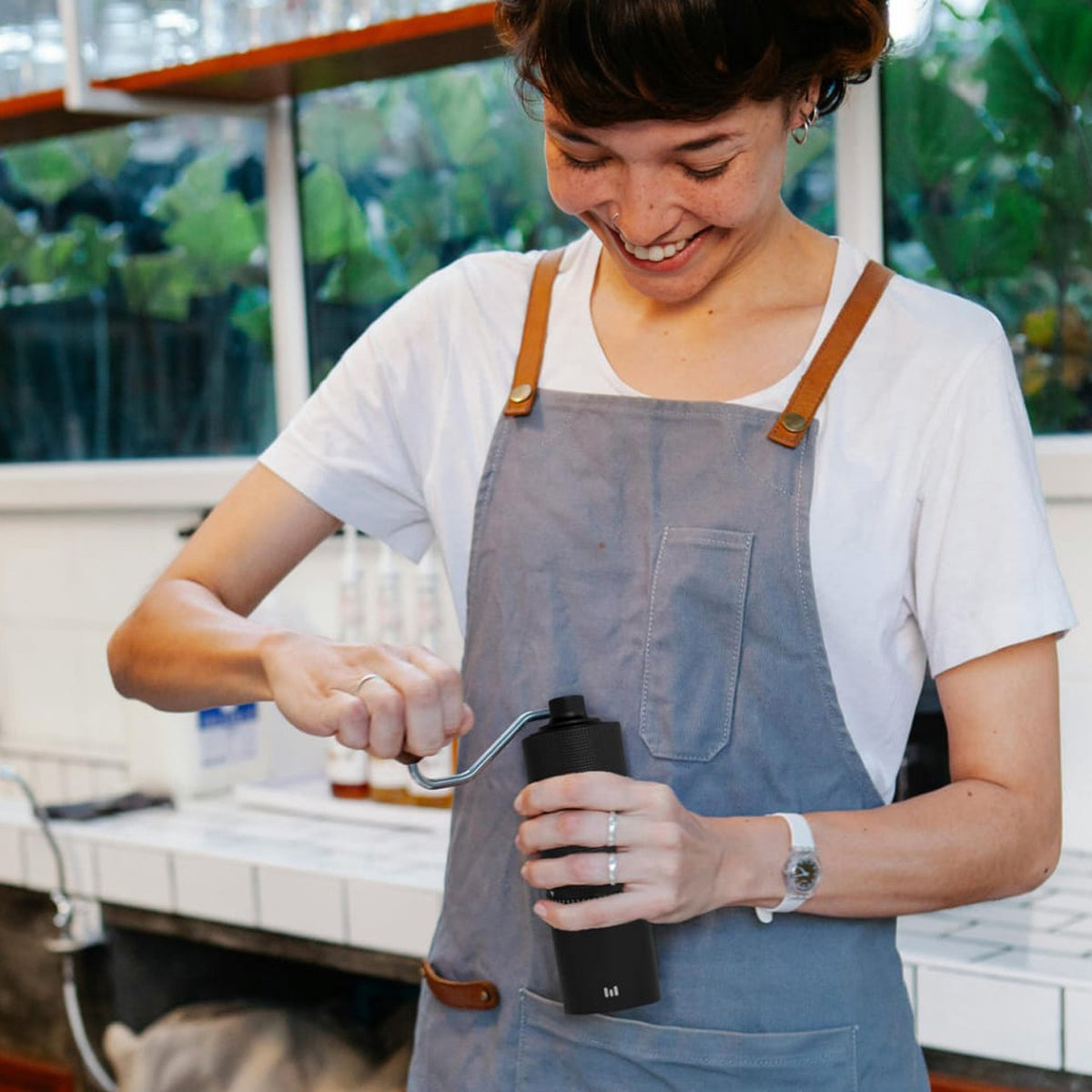 A Women is Making Coffee Using Macnoa MacGrind Craft - Manual Hand Coffee Bean Grinder.