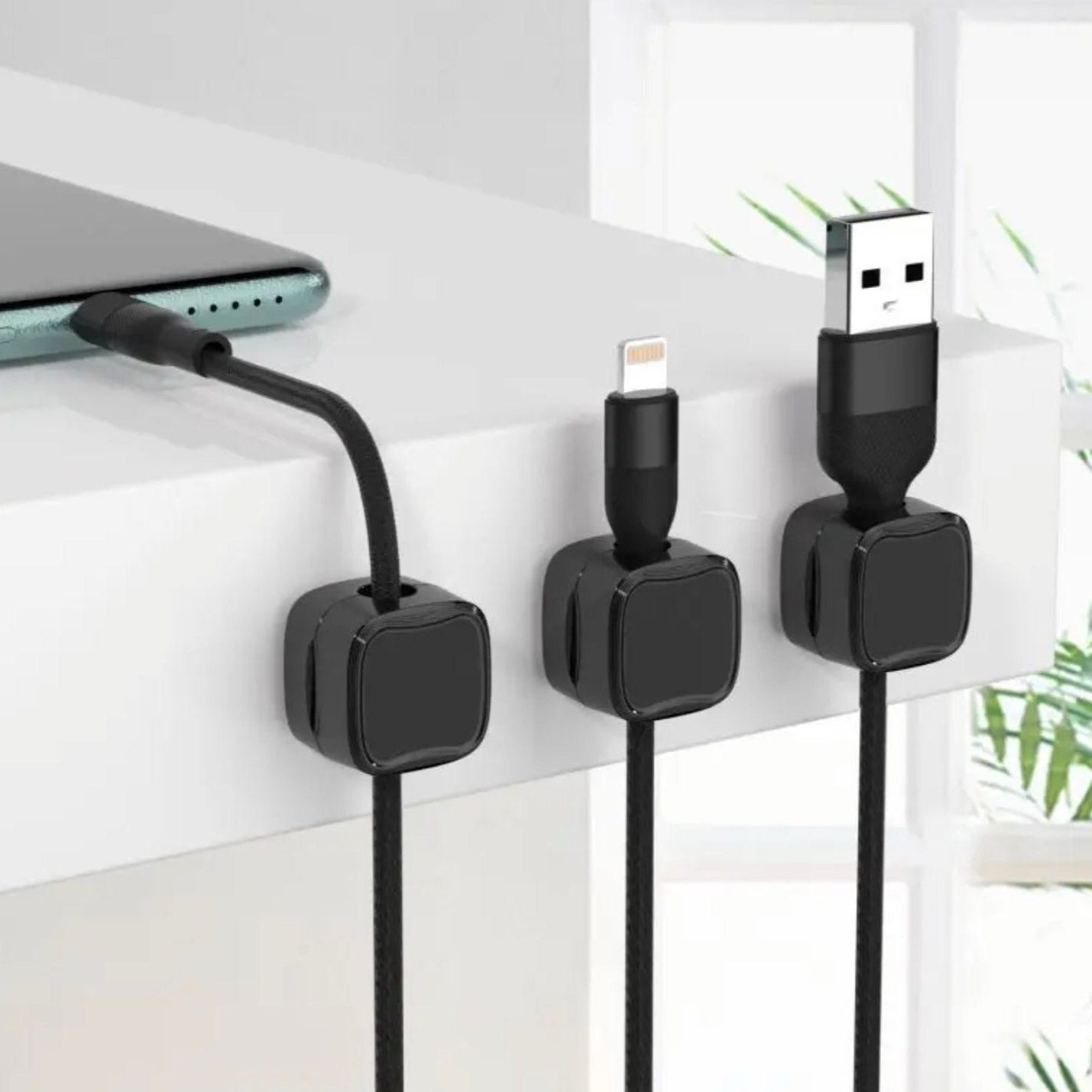 Self-adhesive clips securely hold charging cables on desk edges.