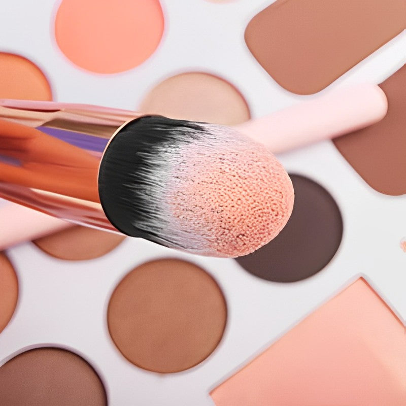 A makeup brush is being used on a palette of eyeshadows from the 16-Piece Makeup Brushes Set Kit with Premium Synthetic Bristles and an Eyebrow Razor