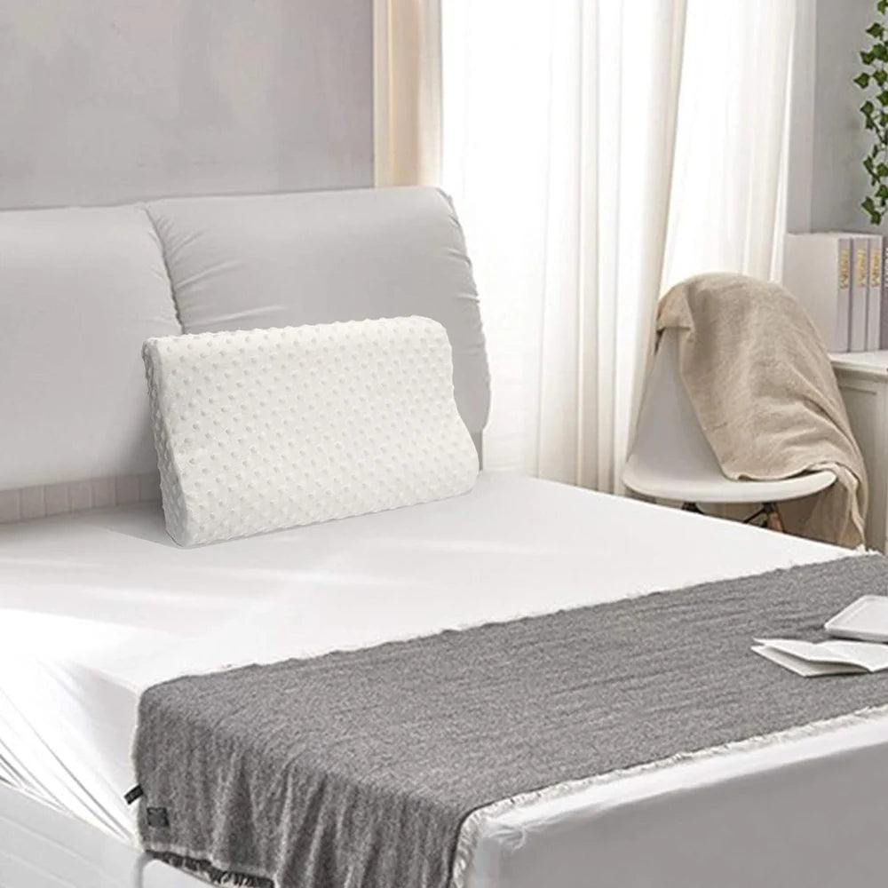A white memory foam pillow placed on a neatly made bed in a calm, modern bedroom setting