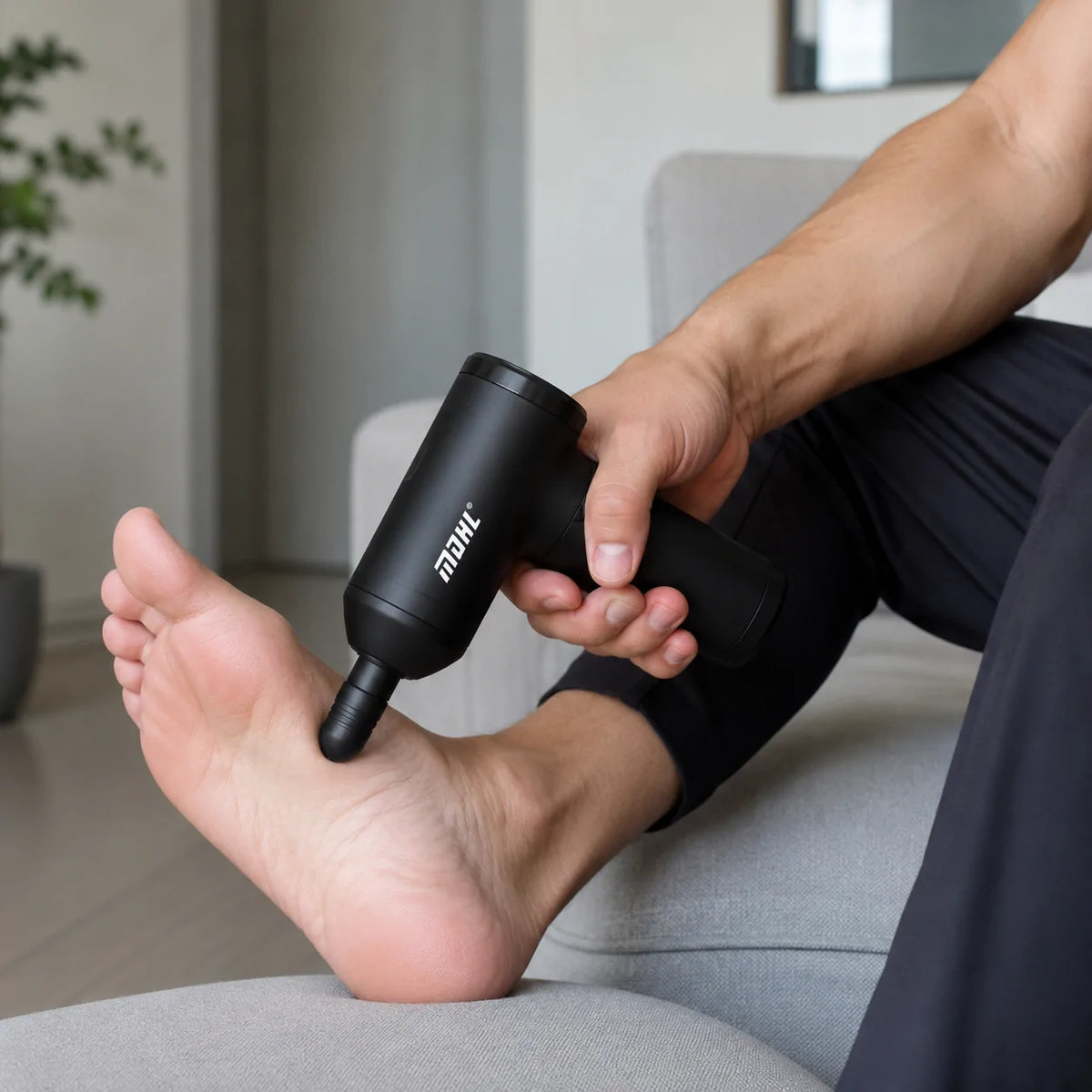 A Person is using Mini Massage Gun on his legs.