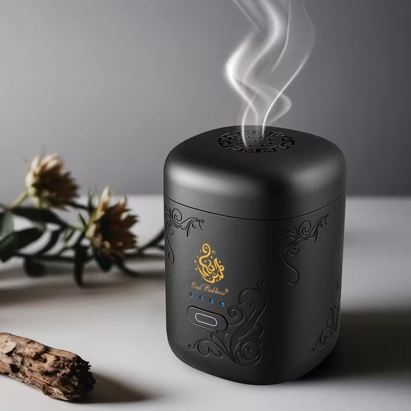 Mini Portable Electric Bakhoor Burner with intricate designs and steam rising, placed on a light surface with a blurred plant in the background.