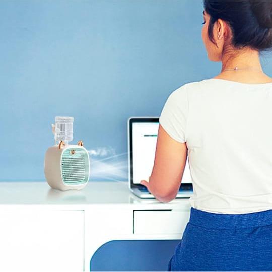 A Women is Working On Laptop By Placing Mini Spray Cooling Fan On The Desktop.