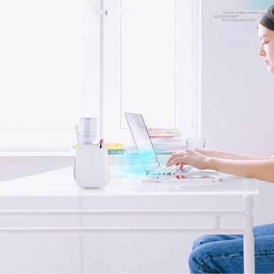 A Women is Working On Laptop By Placing Mini Spray Cooling Fan On The Desktop.