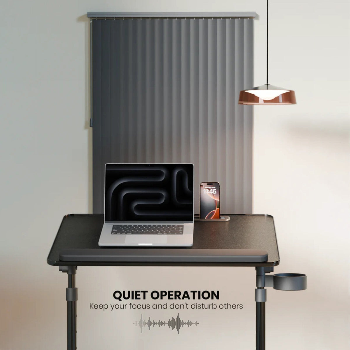 A Moxedo FlexMate Adjustable Height Laptop Desk with adjustable legs, shown in a minimalist office setting with a laptop, smartphone, and a hanging pendant light. The desk features a cup holder on the side and text overlay that reads 'QUIET OPERATION Keep your focus and don't disturb others'.