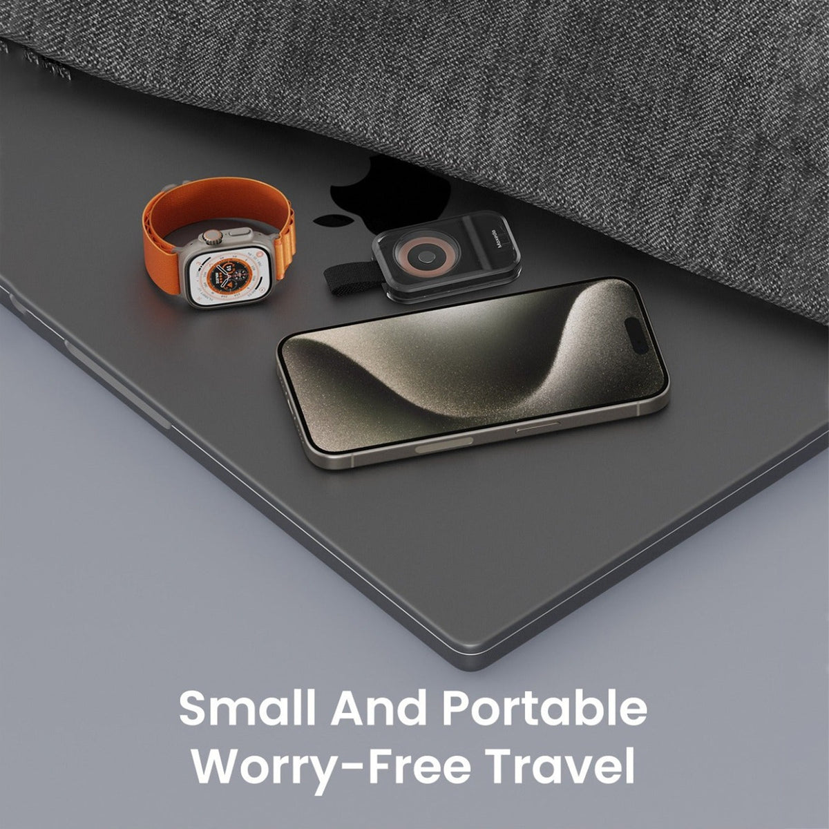 A Moxedo Portable Wireless Magnetic Watch Charger resting on top of a dark gray laptop, alongside an orange watch band and a smartphone. Text at the bottom reads 'Small And Portable Worry-Free Travel'.