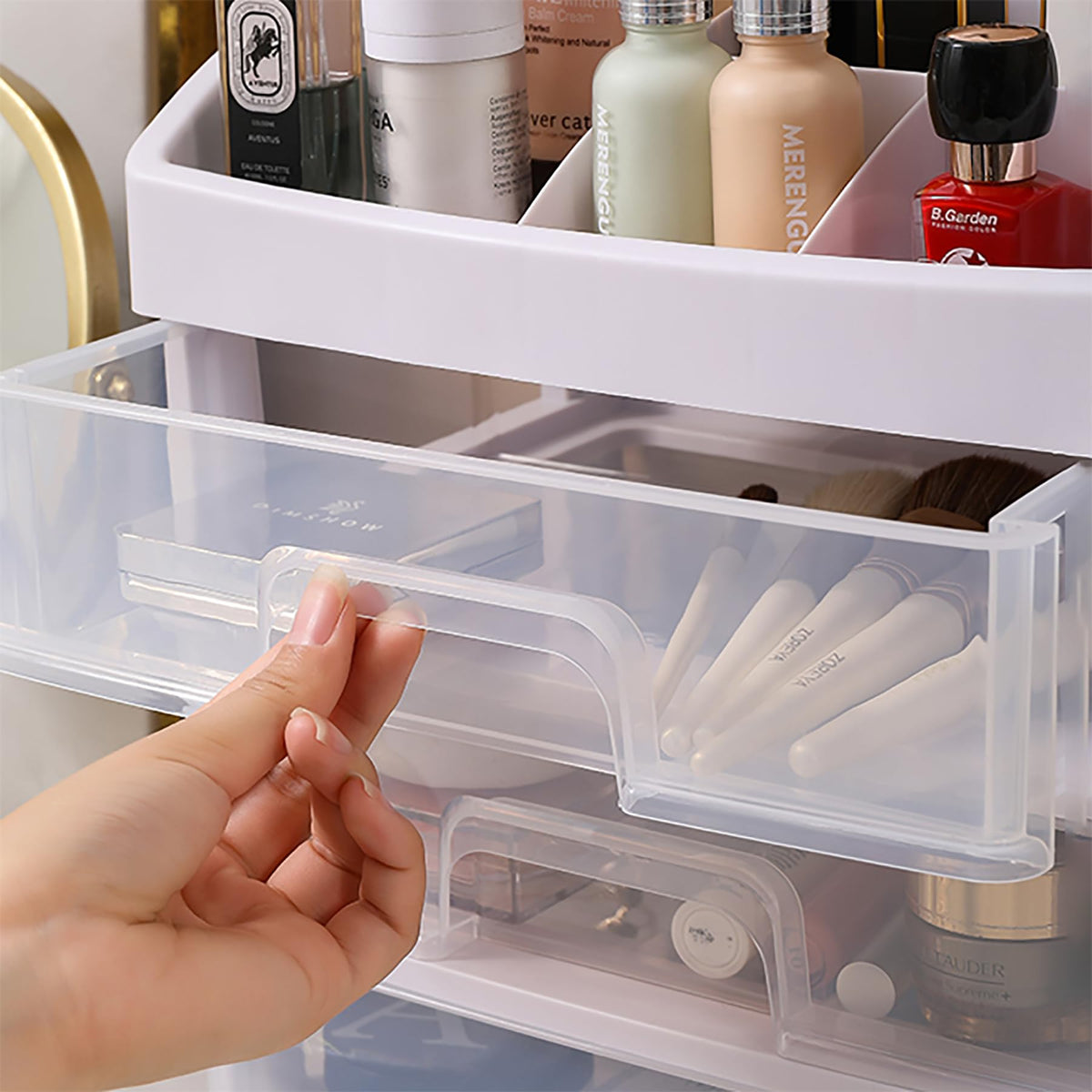Hand opening a clear plastic drawer of Multi-Compartment Makeup Organizer filled with various skincare products.