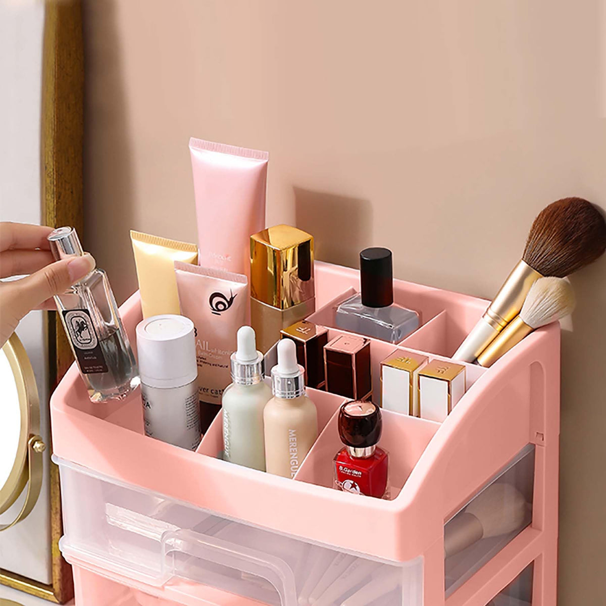 A Person is taking perfume from Pink makeup organizer with various cosmetic items on a beige wall background