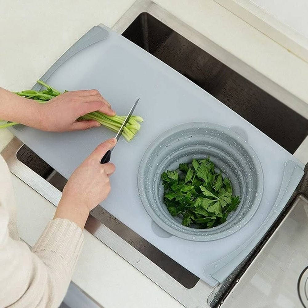 A Person is Cutting Veggies in a Multifunctional Chopping Board Placed On a Kitchen Sink.