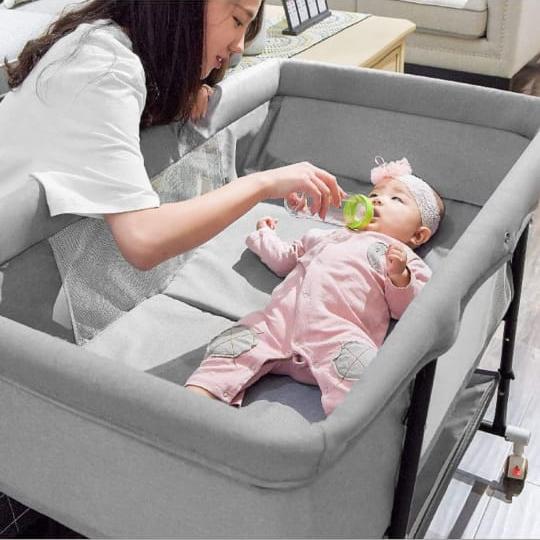 A Mother is Feeding Her Baby Lying Inside a Newborn Baby Cradle.