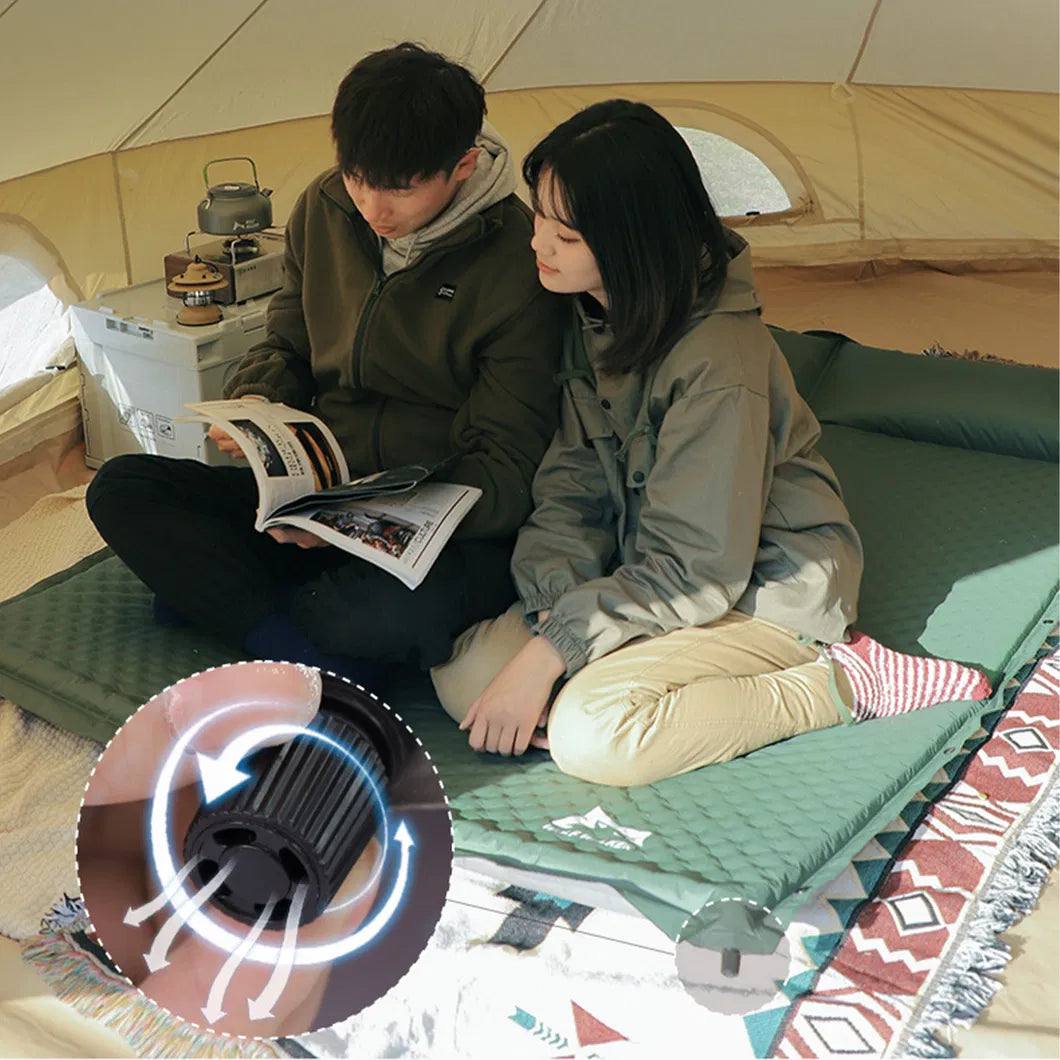Couple sitting inside a camping tent on a green self-inflating camping mattress with built-in pillow.
