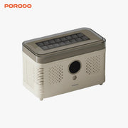 A PORODO FrostIQ Portable Ice Cube Maker shown at a three-quarter angle on a light gray background, featuring a beige body, a dark gray translucent top lid, and a circular front lens opening.