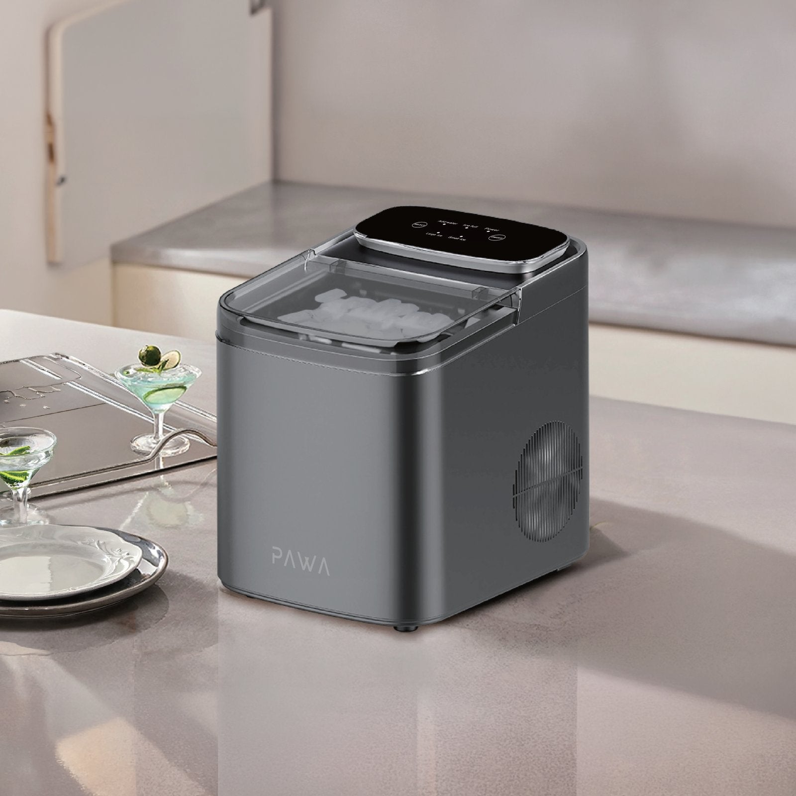 Pawa Chiller Portable Ice Maker with a clear lid showing ice cubes inside, placed on a light beige kitchen counter. The brand name PAWA is visible on the front, with a small digital control panel on top.