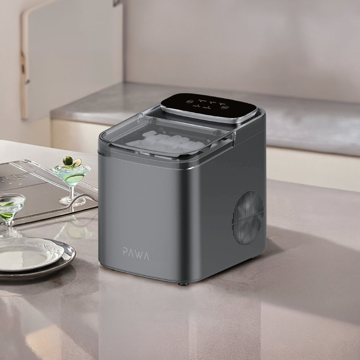 Pawa Chiller Portable Ice Maker with a clear lid showing ice cubes inside, placed on a light beige kitchen counter. The brand name PAWA is visible on the front, with a small digital control panel on top.