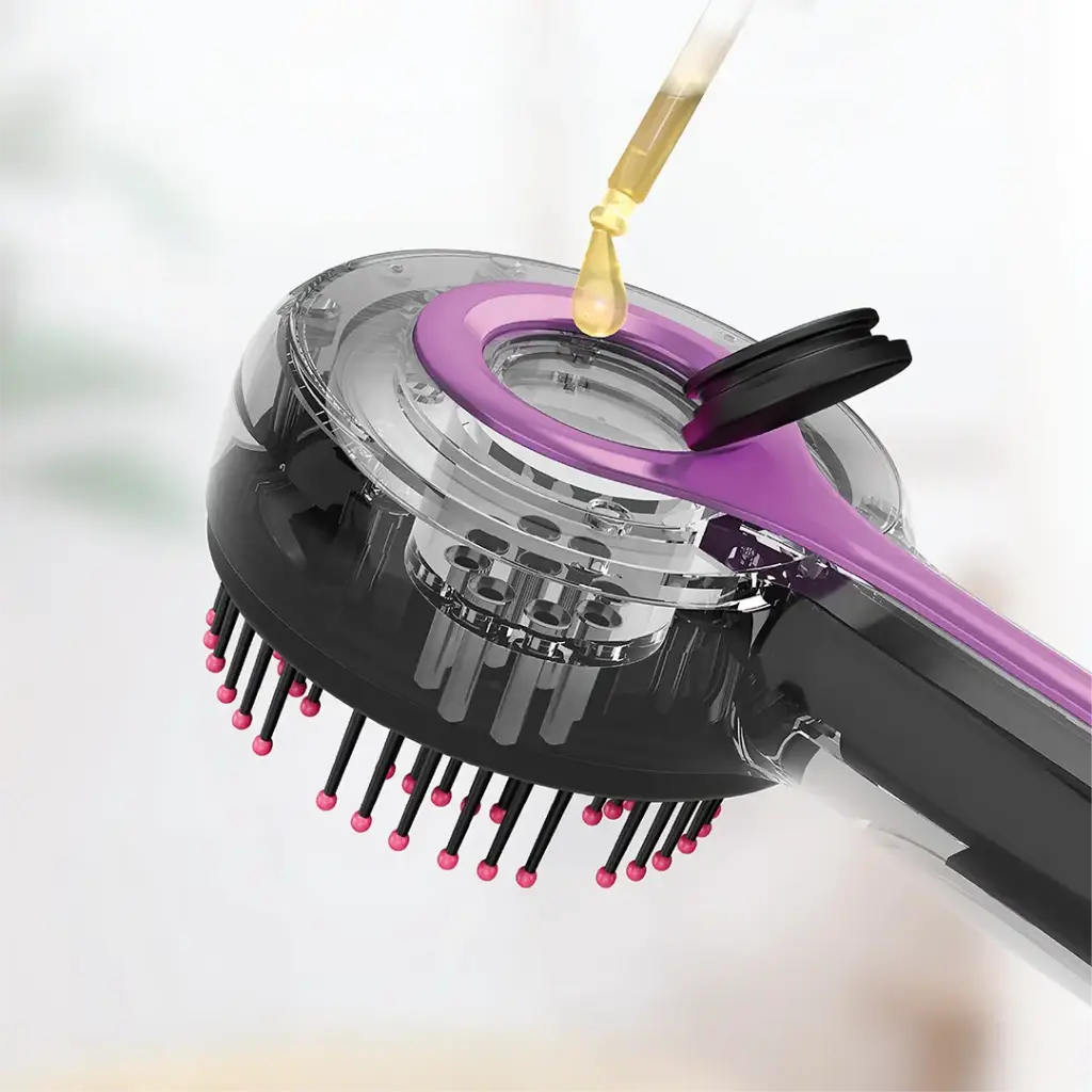 orodo red light therapy scalp massage comb is shown in close-up, featuring soft bristles with rounded tips and a transparent chamber at the top. A dropper is adding liquid (likely hair oil or serum) into the comb’s built-in reservoir through an open cap.