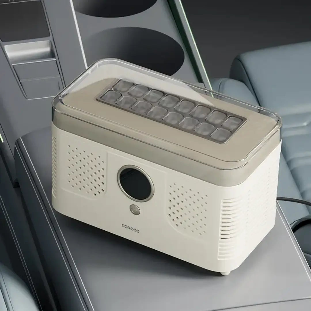 A PORODO FrostIQ Portable Ice Cube Maker with a cream body, beige top panel, and clear lid, shown resting on a car center console between seats.