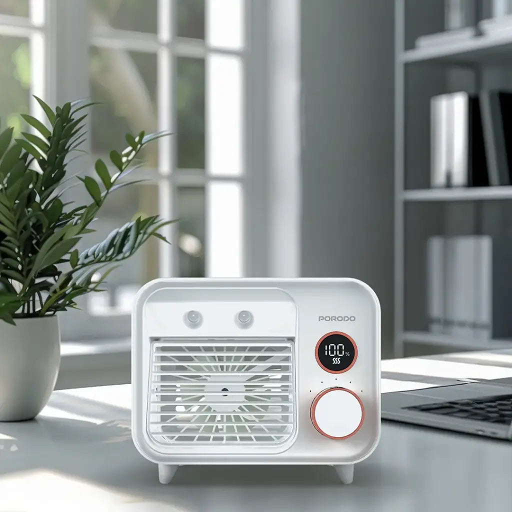 Small white Porodo Mini Mist Fan Desktop Air Cooler on a desk next to a plant and laptop