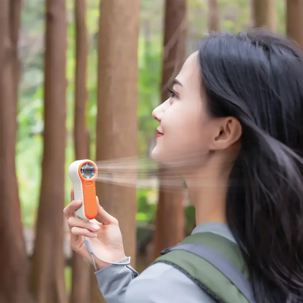 Woman using a Porodo Pocket Size Handheld Fan in a forest setting