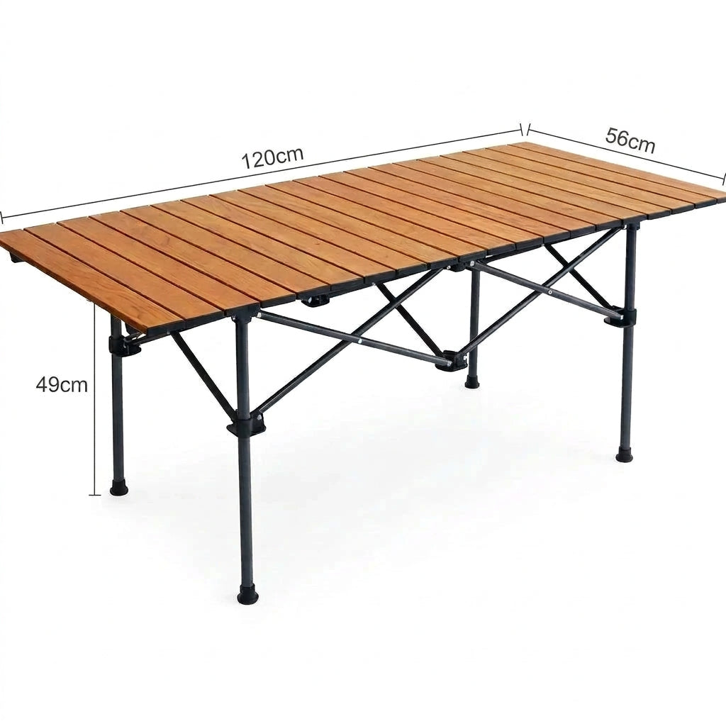 A portable folding camping table with a warm brown wood-look slatted top and a black metal frame, shown on a plain white background.