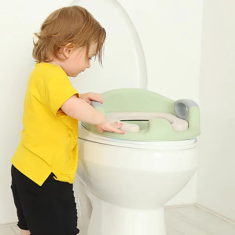 A baby is trying to fit on the Potty Training Toilet Seat with Soft Cushion Handles