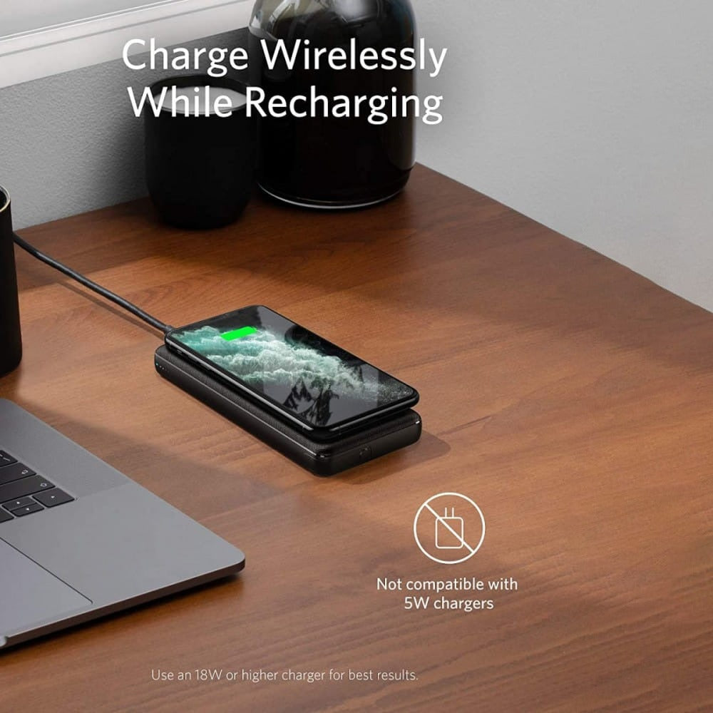 On the table, an Anker 10W PowerCore III Sense 10K Wireless Power Bank is neatly placed, efficiently charging a phone placed next to a sleek laptop