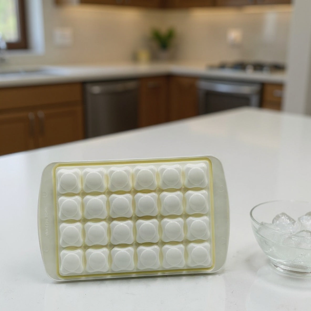 An Ice Cube Tray is Placed on a Kitchen Cabinet Along with a Bowl of Ice Cubes.