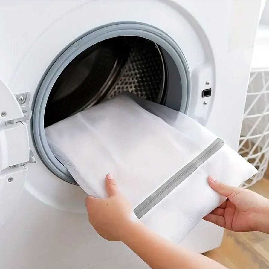 A Person is inserting cloth to a washing machine using 4 Pcs  Mesh Laundry Washing Bags Set.