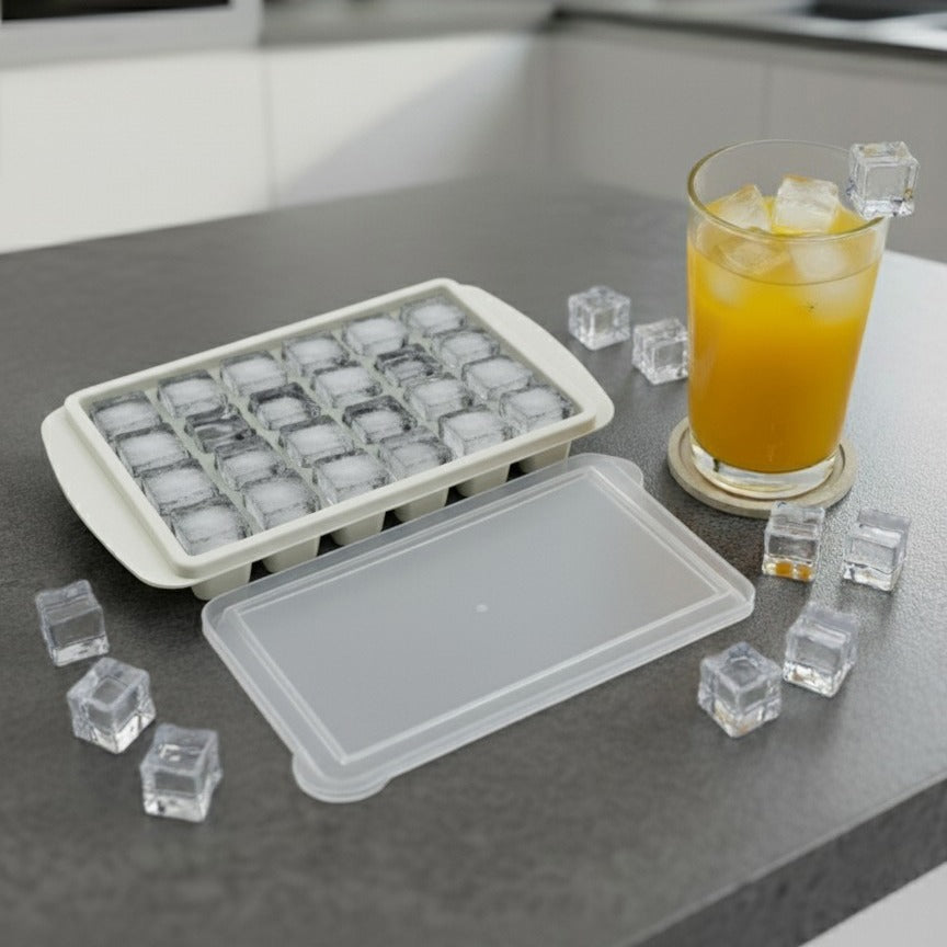 An Ice Cube Tray is Placed on a Kitchen Cabinet Along with a Glass of Juice.