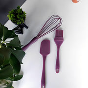 A brush and spatula placed on a white floor, surrounded by green leaves.
