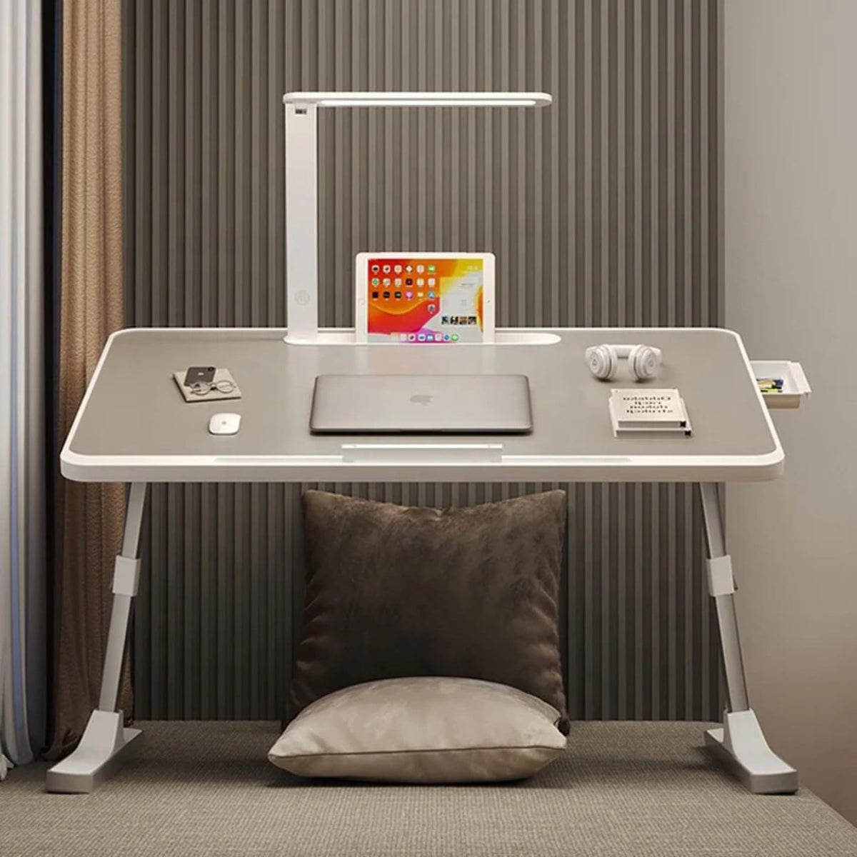 Portable foldable laptop bed desk table with adjustable legs and built-in LED lamp, arranged with laptop and other essentials.