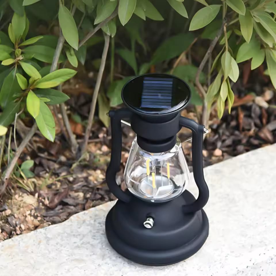 Solar-powered lantern placed on the ground near green foliage.