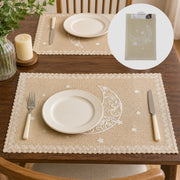 Table setting with decorative placemats featuring moon and star designs on a wooden table.