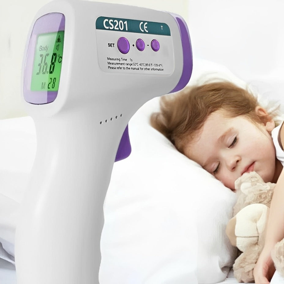 A digital infrared thermometer with an LCD display showing temperature, positioned near a sleeping child holding a teddy bear, highlighting safe and contactless temperature measurement.