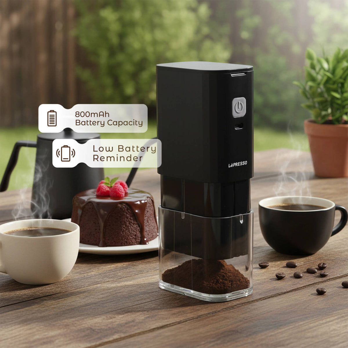 Lepresso JetGrind Rechargeable Coffee Grinder placed on a wooden outdoor camping table, compact cordless design with built-in 800mAh rechargeable battery, low battery reminder indicator glowing, transparent coffee bean chamber, and fresh coffee beans nearby