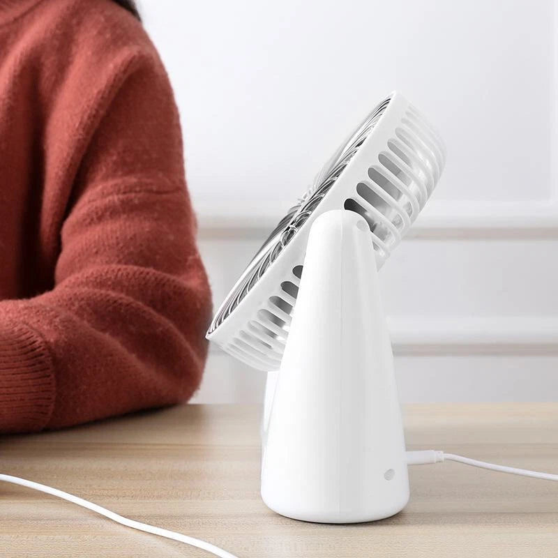 Rechargeable USB Desktop Fan on a wooden surface with a person wearing a red sweater in the background.