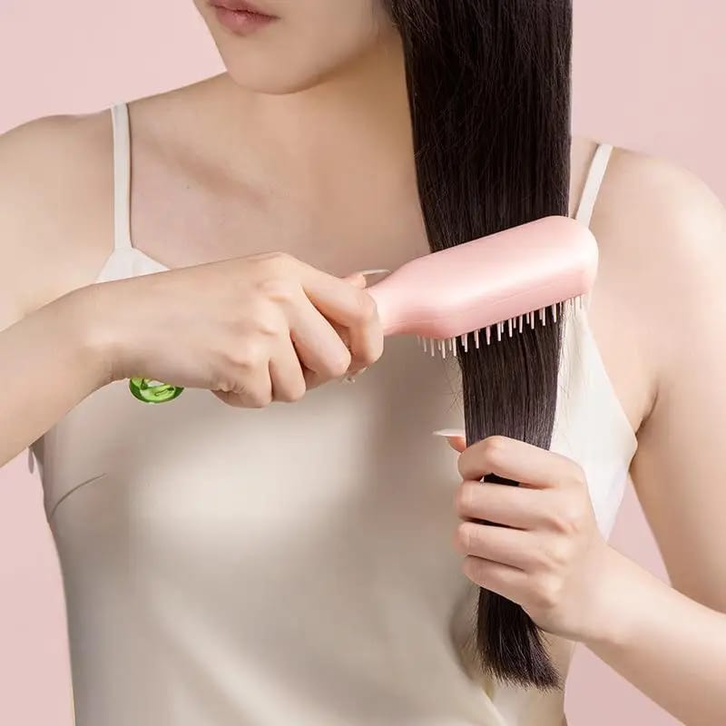 A Women is Combing Her Hair Using Retractable Self Cleaning Hair Brush.