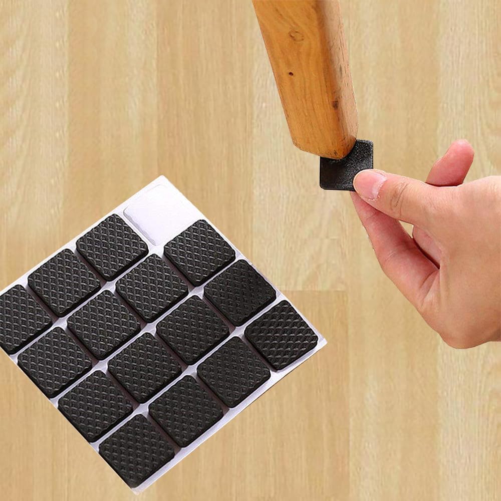 A hand holds a Self-Adhesive Furniture Pads against a wooden floor and trying to fix on a chair leg, with a sheet of multiple matching black floor pads shown in the lower left on a light wood background.