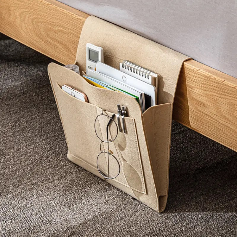 Felt Bedside Storage Bag placed next to the bed with some items